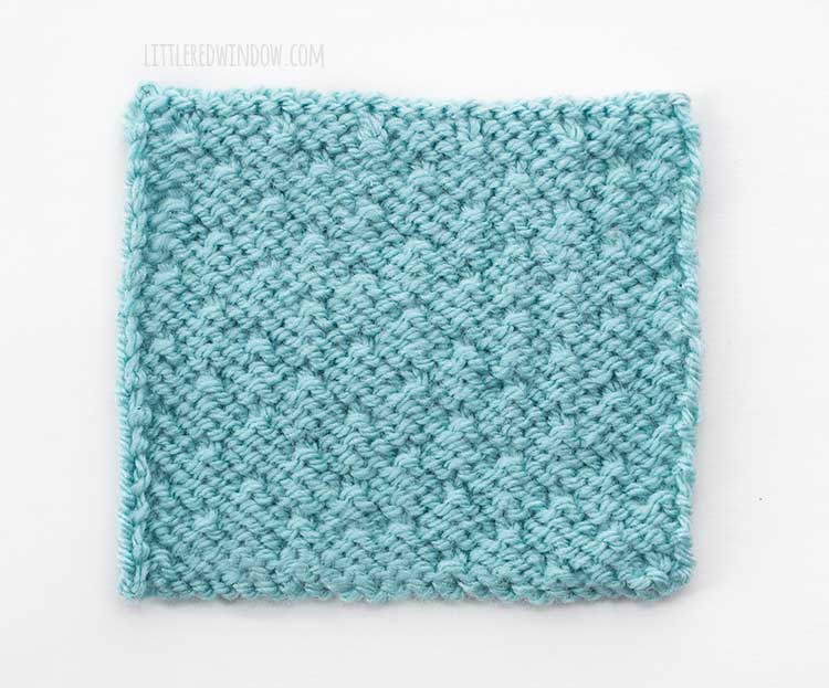 the wrong side of a light blue square swatch of dot stitch knitting on a white background