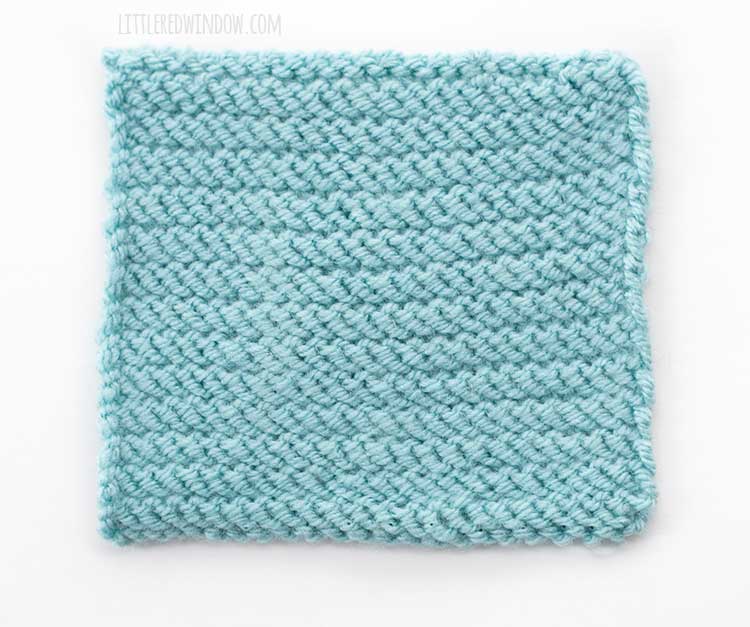 the wrong side of a light blue square of twisted stockinette stitch knitting on a white background