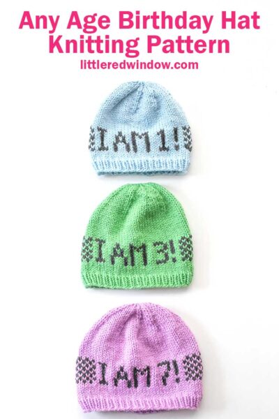 Three knit hats on a white background in light blue light green and lavender with the words I am 1 3 and 7 on them