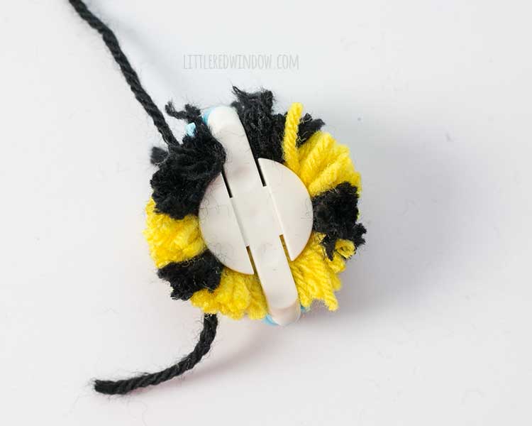 pom pom maker with eighteen inches of black yarn tied around the middle