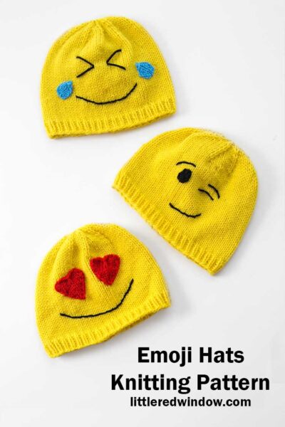 three yellow knit emoji hats lying flat on a white background