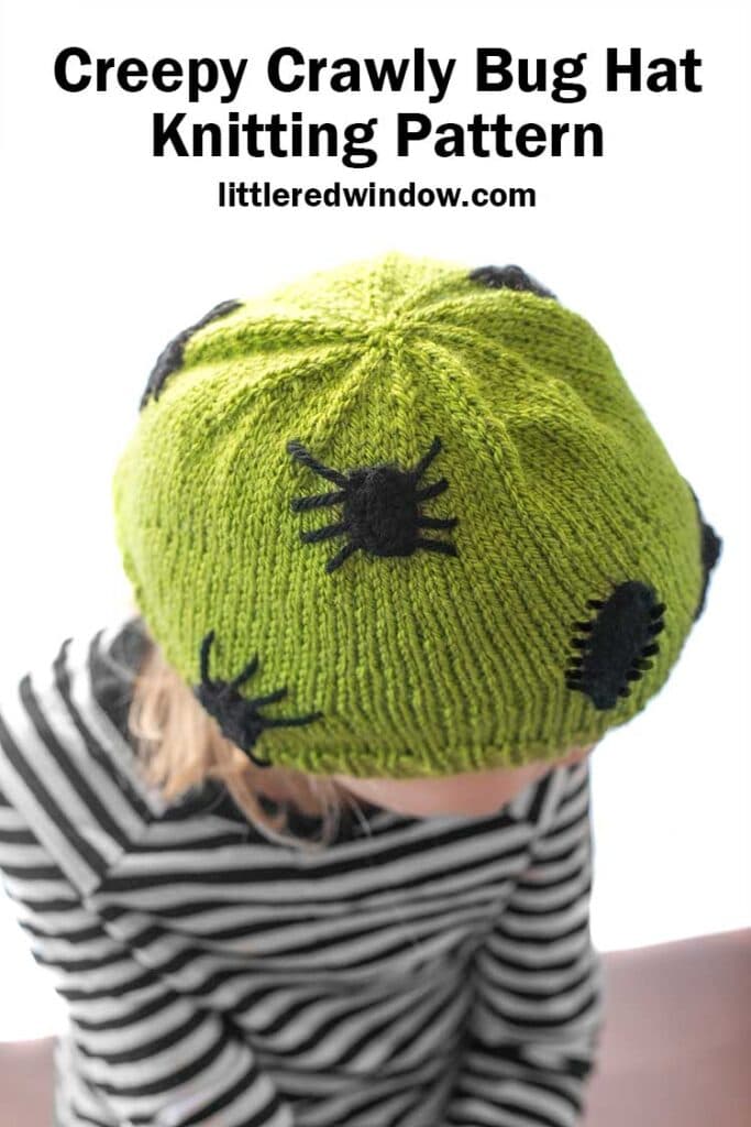 child in black and white striped shirt wearing an acid green knit hat with black knit spiders and bugs on it leaning forward and looking off to the right in front of a white background