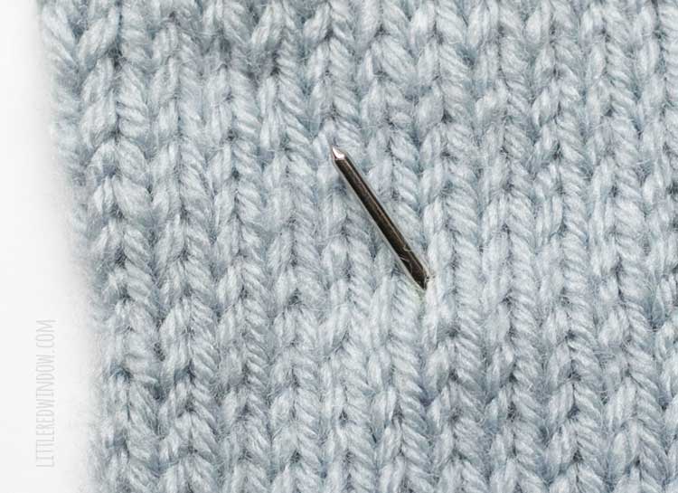 light blue stockinette stitch swatch with a yarn needle coming through in the middle