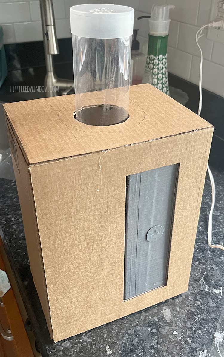 assembled cardboard box pencil sharpener with a clear plastic tube sticking out of a hole on the top