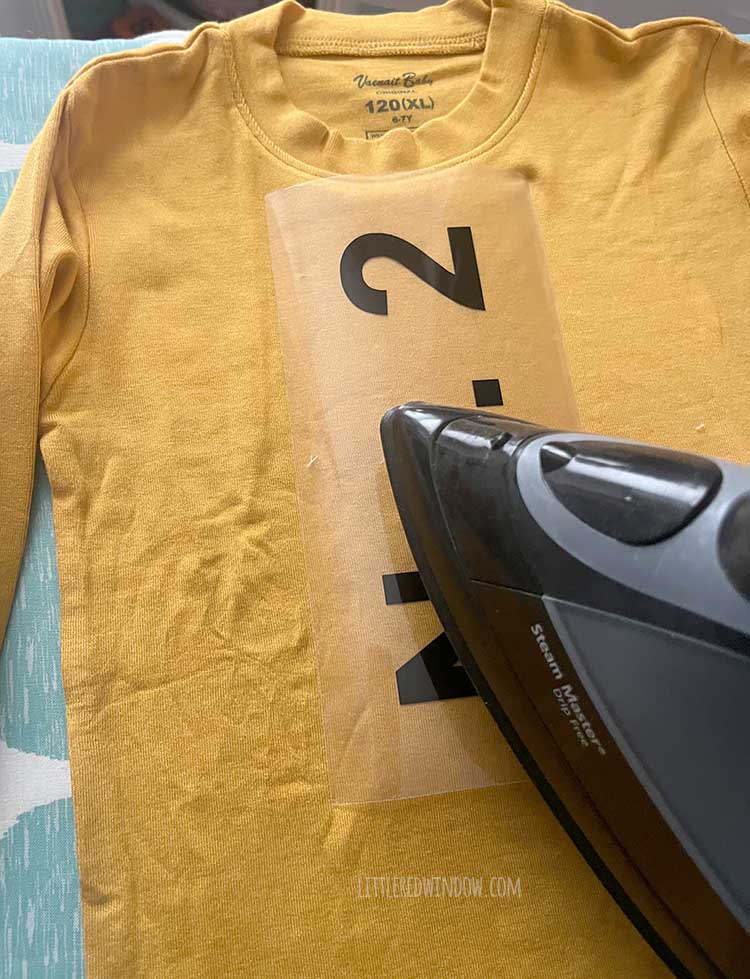 An iron ironing the heat transfer vinyl No 2 onto the yellow pencil costume shirt