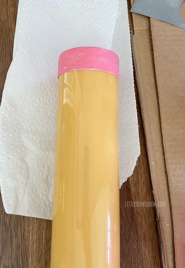 close up of yellow painted plastic tube with a pink painted top on one end on top of a table
