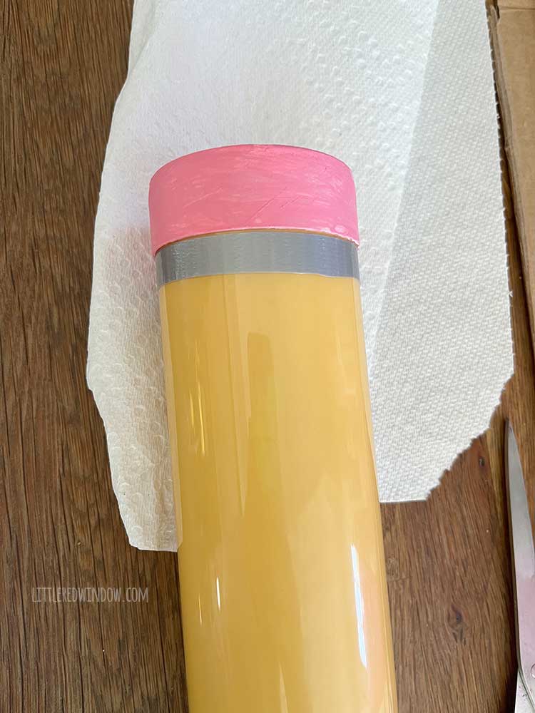 Yellow plastic tube with pink top with one small strip of silver duct tape added under the pink top to make it look like the end of a pencil