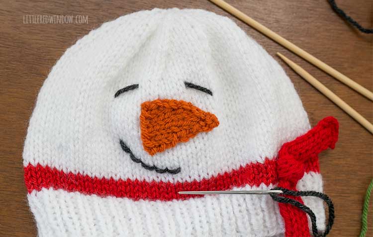closeup of finished snowman face with carrot nose and smile