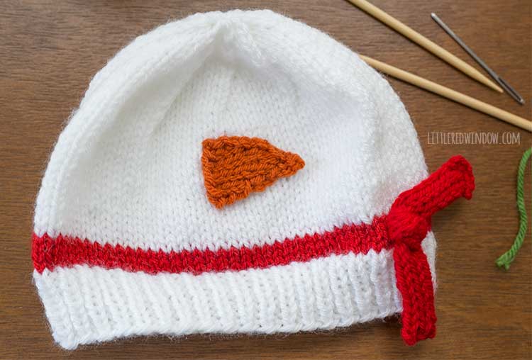 white knit hat with an orange sideways triangle sewed to the front to be a carrot nose