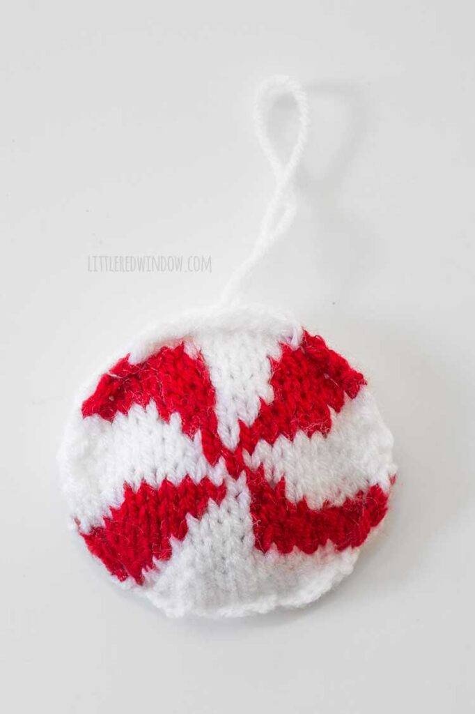 closeup of round knit red and white peppermint candy Christmas tree ornament