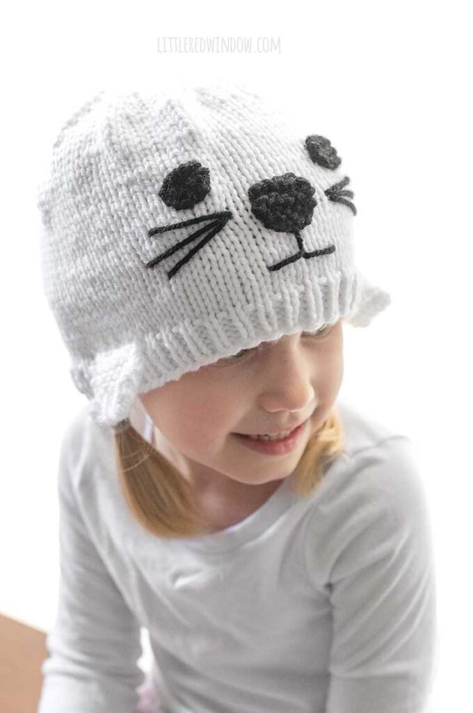 closeup of girl wearing white seal knit hat and looking off to the right