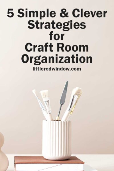 what paintbrushes and art tools in a white jar on top of a tan book