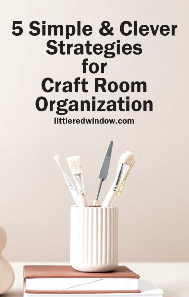what paintbrushes and art tools in a white jar on top of a tan book