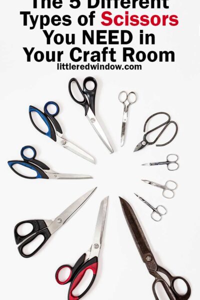 11 pairs of scissors of various sizes arranged blades inward in a circle on a white background