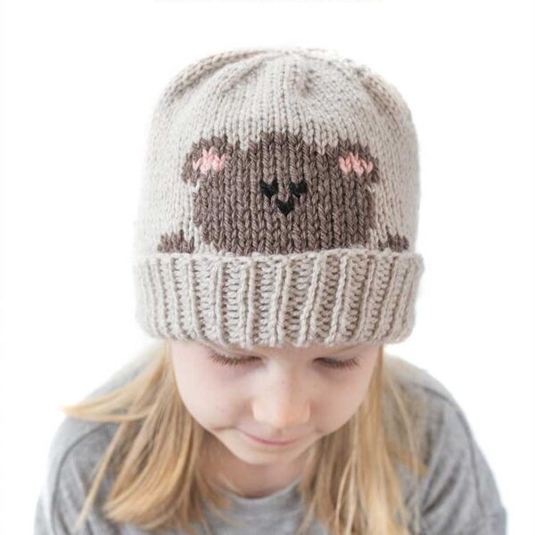 blonde girl in gray shirt looking down wearing a tan knit hat with a folded brim that has a brown teddy bear head peeking over the brim