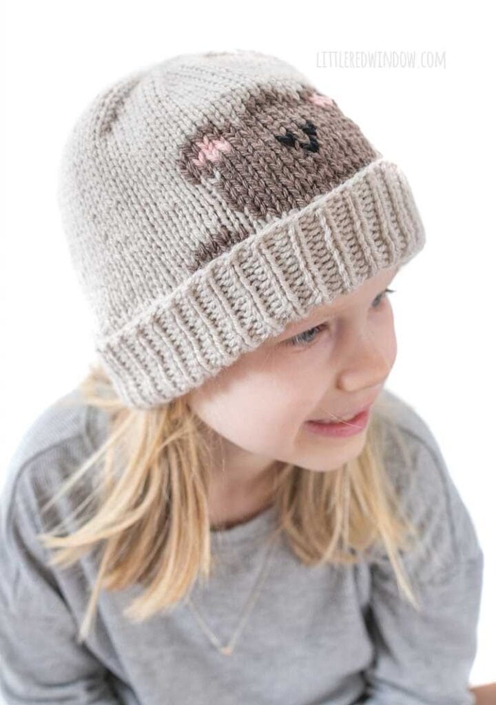 view from slightly above left of the duplicate stitch teddy bear patter on a tan knit hat with folded brim