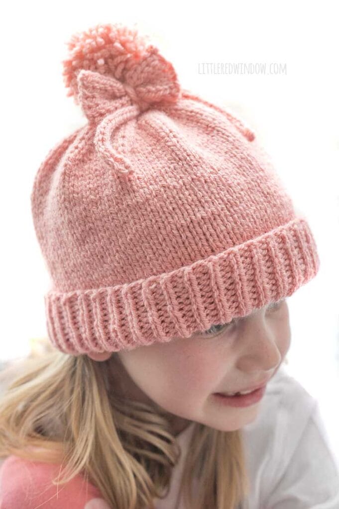 Closeup of the pom pom bow hat in medium pink