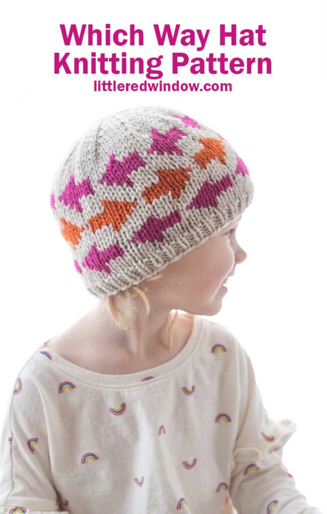 little girl wearing tan knit hat with pink and orange arrow shapes on it looking off to the right