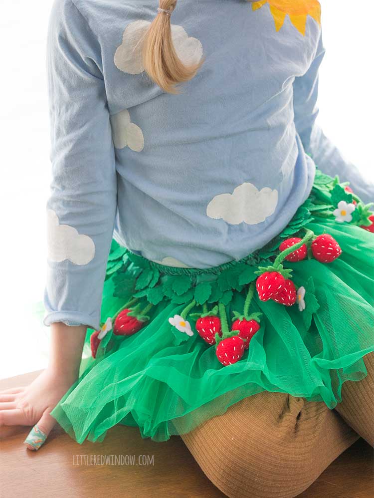 closer view from above of strawberry fields costume skirt made from a green tutu covered with felt strawberries white flowers and green felt leaves