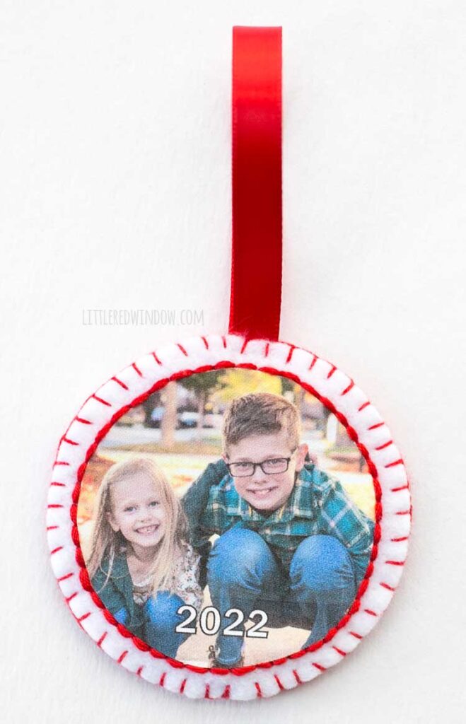 round red and white felt photo ornament with red ribbon hanging loop in front of a white background