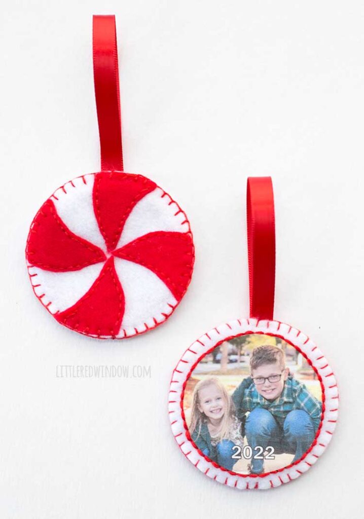 two round red and white felt ornaments one with a photo of kids on it and the other that looks like a peppermint candy with red hanging ribbons