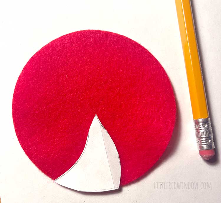 red felt circle with one white paper template peppermint candy section on top next to a pencil on a white background
