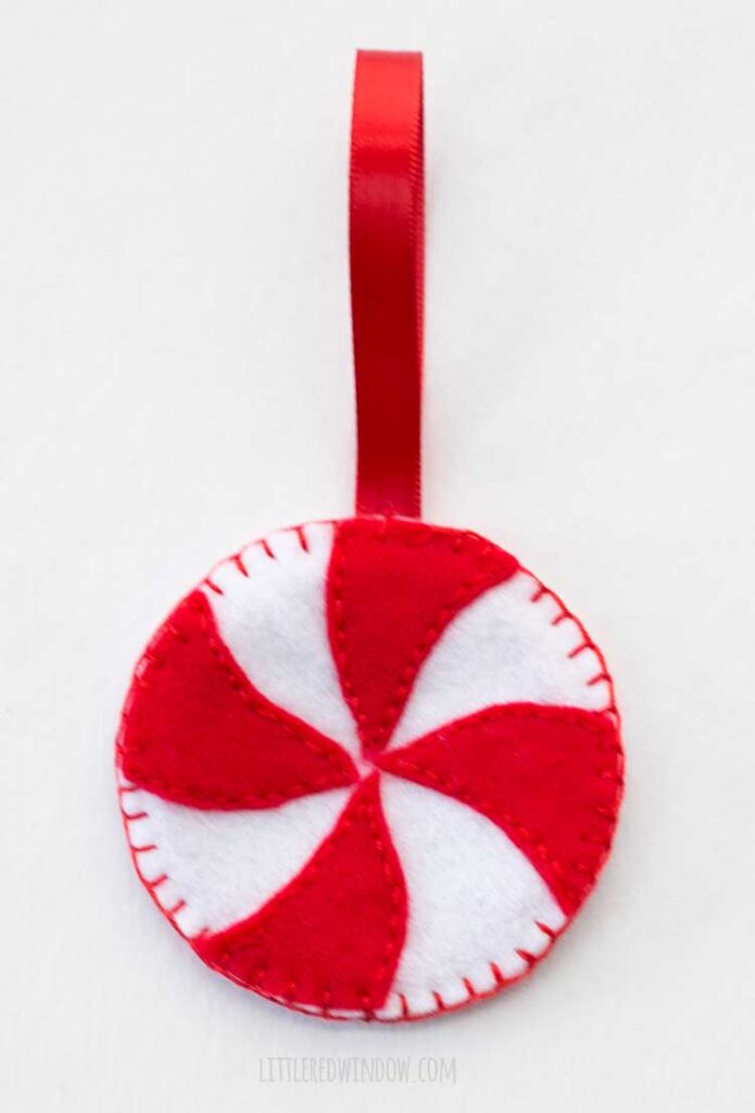 the back side of peppermint candy felt ornaments with red ribbon hanger on a white background