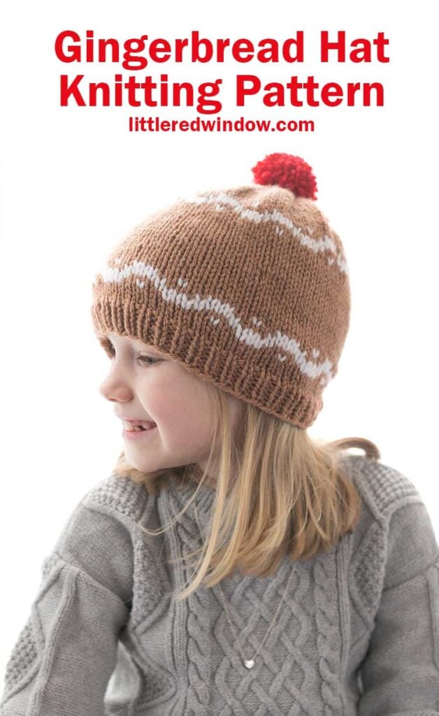 girl in gray sweater wearing a medium brown hat with white designs that look like gingerbread and a red pom pom on top looking off to the left