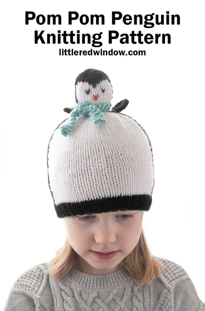 Blonde girl in a black and white hat that looks like a penguin wearing a blue scarf looking down at her lap in front of a white background