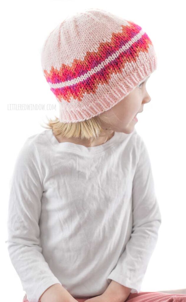 girl in white shirt looking off the right and wearing pink triangle fiery fade hat knitting pattern