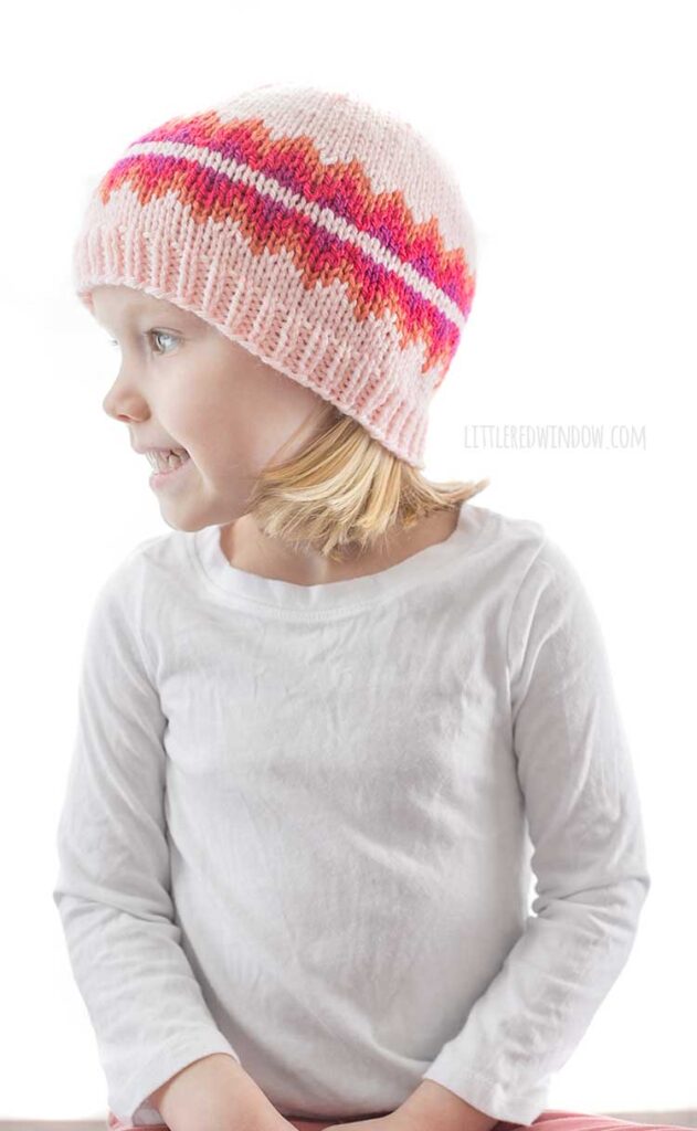 girl in white shirt looking off the left and wearing pink triangle fiery fade hat knitting pattern