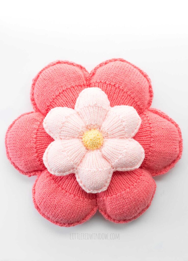top view of large and small flower pillows stacked on top of each other on a white background