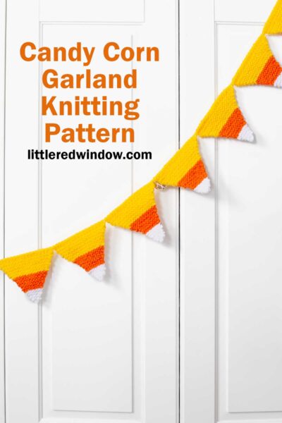 A candy corn garland of knitted yellow, orange, and white shapes hangs across white cabinet doors. Text reads: 