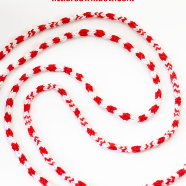 Red and white striped knitted candy cane icord, artfully curved on a white background. Text above reads,