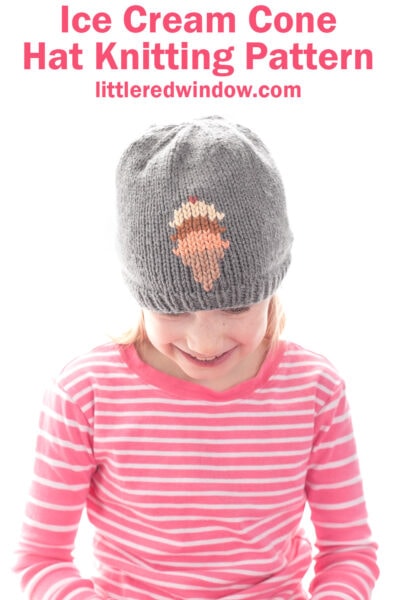 A young child wearing an adorable ice cream cone hat with a gray knit design and a pink and white striped shirt smiles. Text above reads,