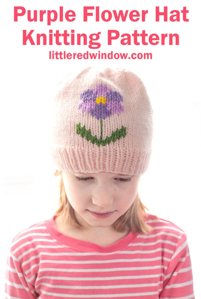 Young girl wearing a light pink flower hat with a purple flower and green leaves design, looking down. Text above reads: