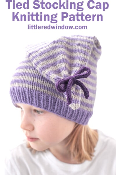 A child wears a purple and white striped tied stocking cap with a bow on the side. Text above reads:
