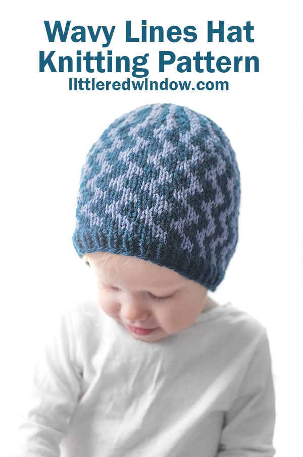 A young child wearing a blue knitted hat featuring Wavy Lines, looking down. Text above reads