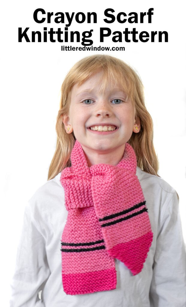 Smiling child wearing a pink and magenta crayon scarf with black stripes over a white shirt. Text above reads,
