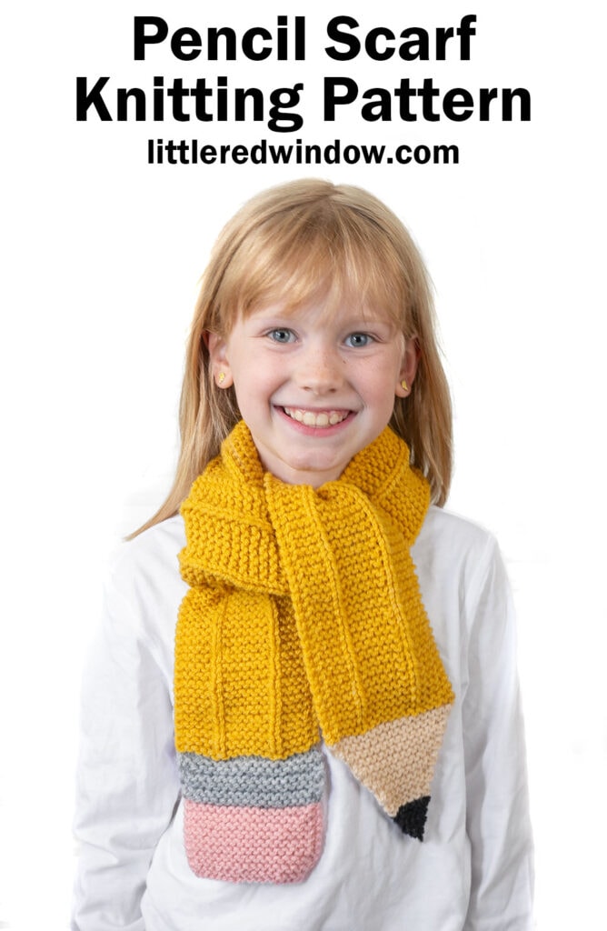 Smiling young girl wearing a scarf designed to look like a yellow pencil, with pink, gray, beige, and black ends. Text above reads