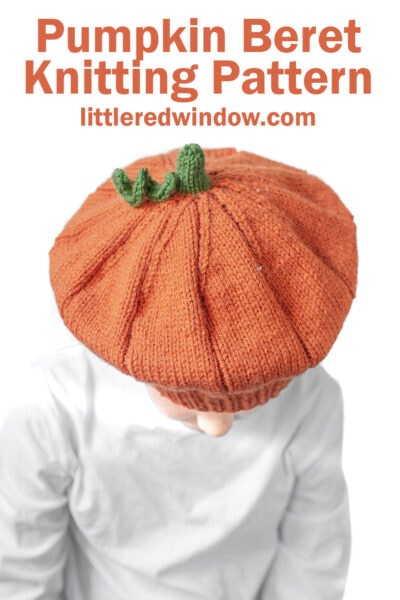 A child wears a pumpkin beret—a knitted orange hat styled like a pumpkin with a green stem on top. Text above reads: “Pumpkin Beret Knitting Pattern littleredwindow.com”.